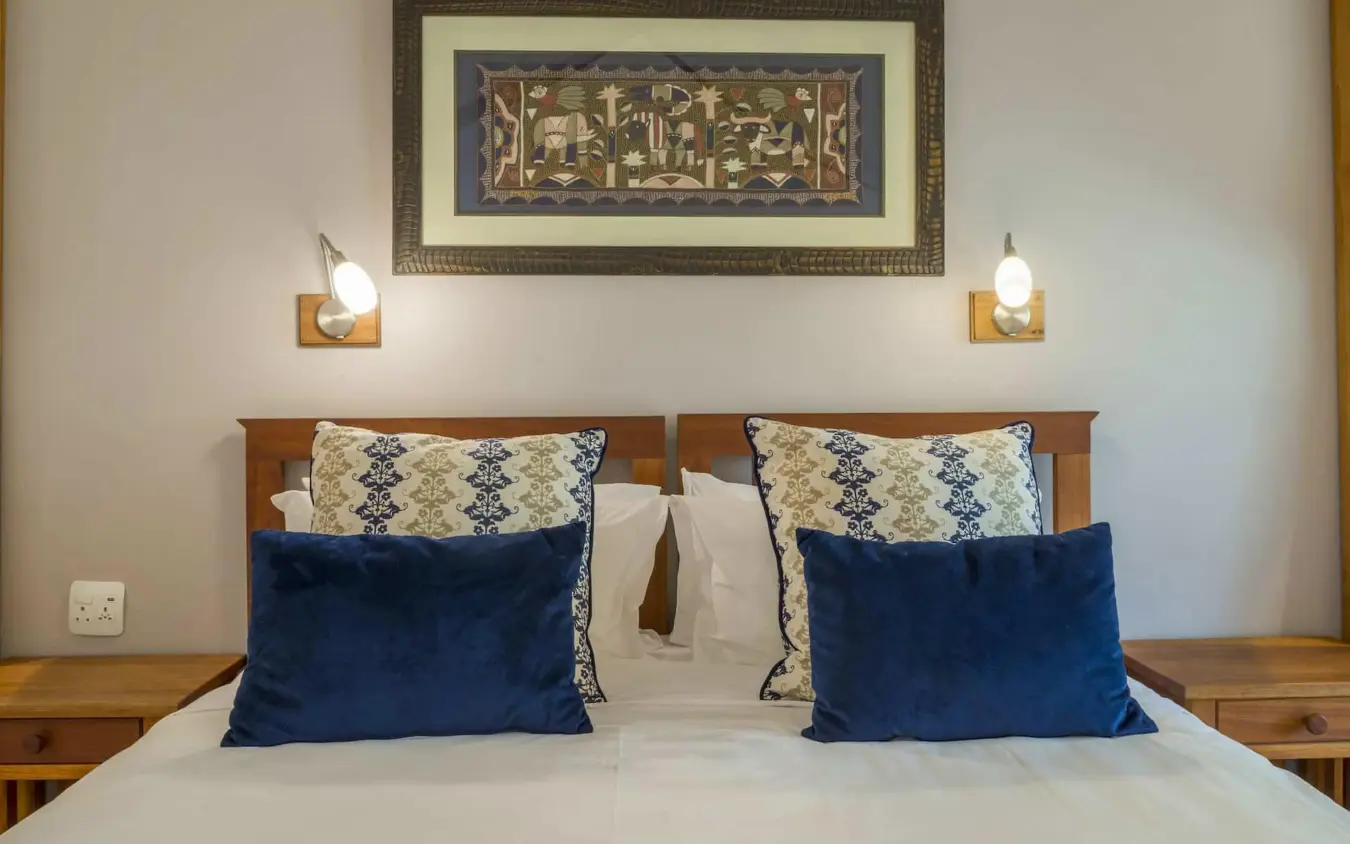 Bedroom with wooden bed frame and blue velvet pillows, Batonka Guest Lodge, Victoria Falls, Zimbabwe