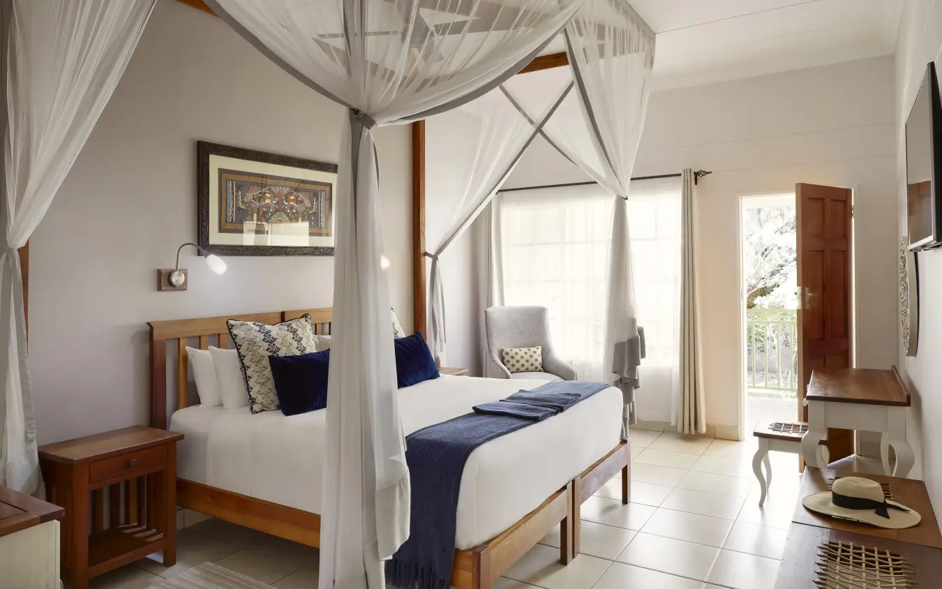Canopy bed with white linens and ocean view doors, Batonka Guest Lodge, Victoria Falls, Zimbabwe