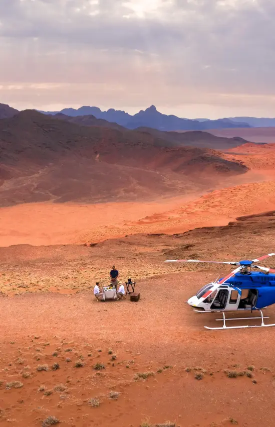 Helicopter landing in vast desert landscape with mountains, Sossusvlei, Namibia