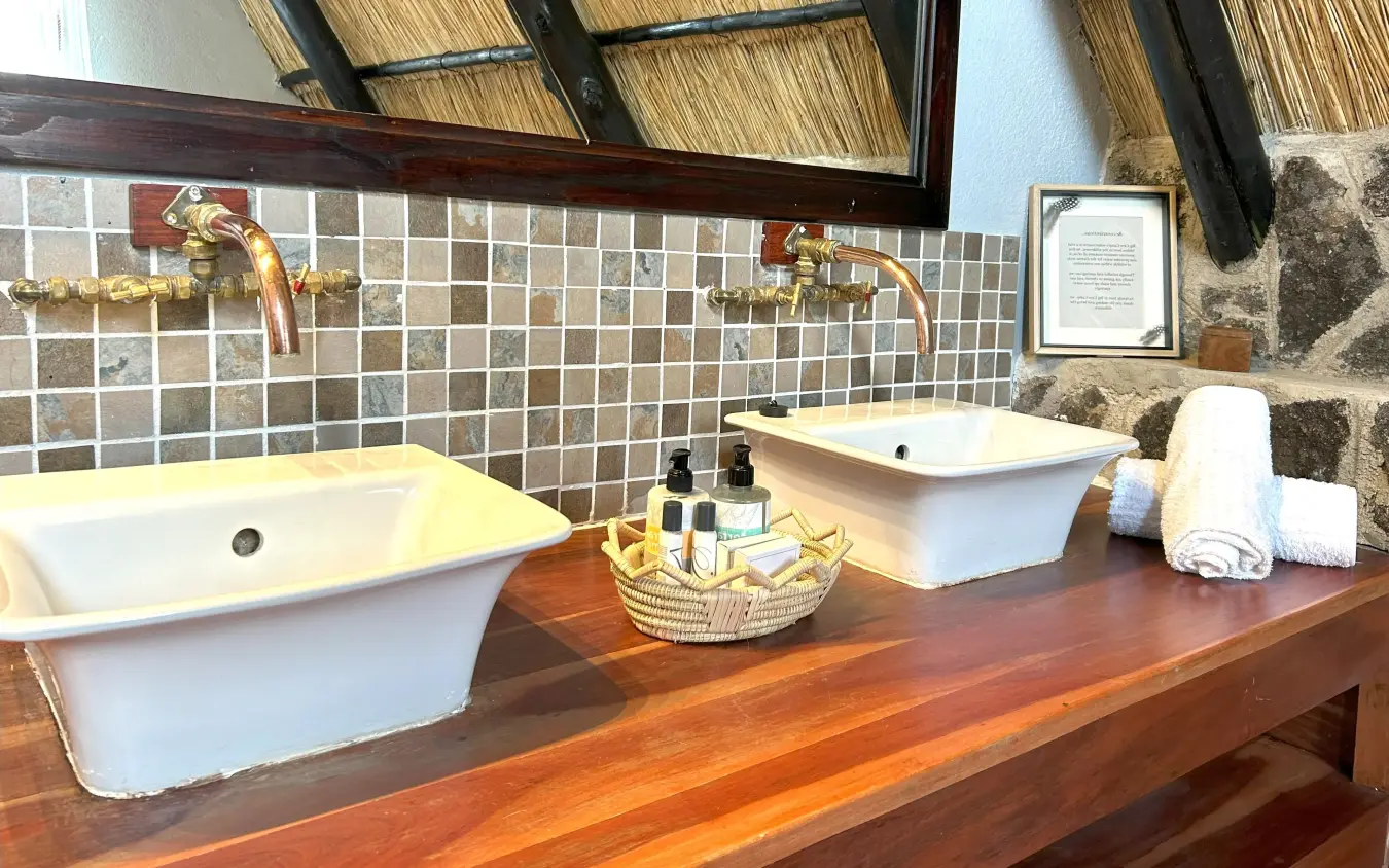 Luxury bathroom with dual vessel sinks and thatched roof detail, Big Cave Camp, Matobo, Zimbabwe