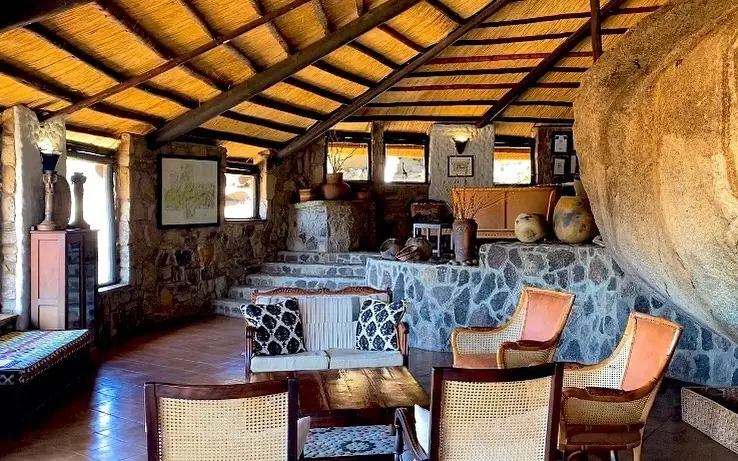 Stone lodge interior with wooden beam ceiling and rustic furnishings, Big Cave Camp, Matobo, Zimbabwe