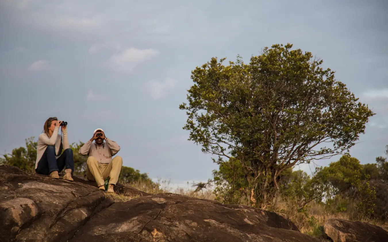 Guests wildlife viewing from rocky outcrop with binoculars, Borana Lodge, Laikipia Highlands, Kenya