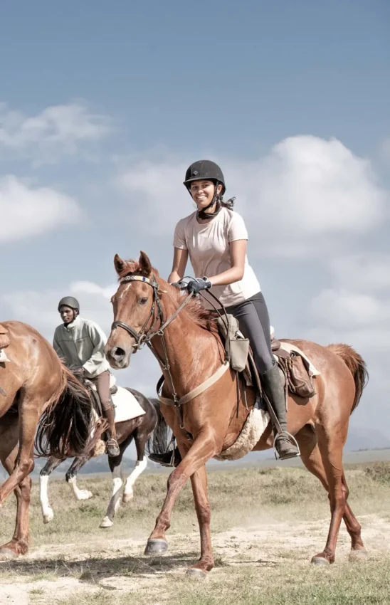 Guests riding horses across open grassland landscape, Laikipia Highlands, Kenya