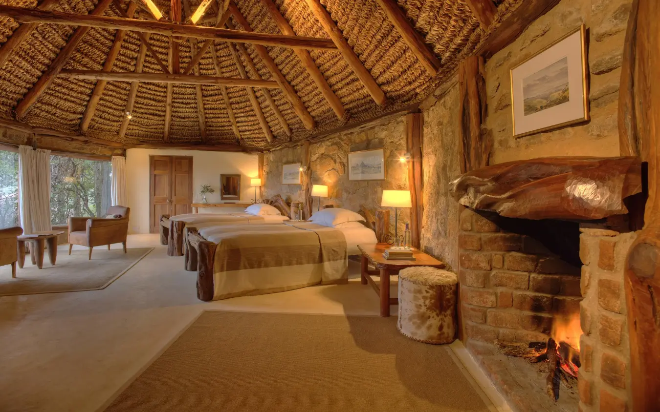 Spacious bedroom with twin beds, fireplace, and thatch ceiling, Borana Lodge, Laikipia Highlands, Kenya