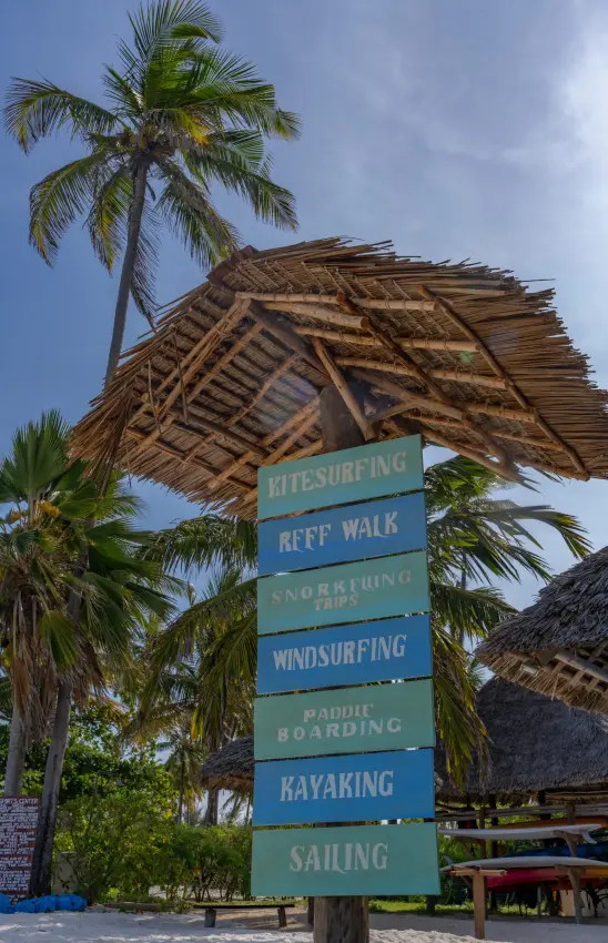 Thatched shelter with water sports signage surrounded by palm trees, Breezes Beach Club & Spa, Zanzibar & Pemba, Tanzania