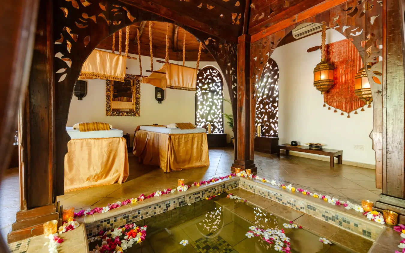 Spa bath with flower petals and carved wooden interior details, Breezes Beach Club & Spa, Zanzibar & Pemba, Tanzania