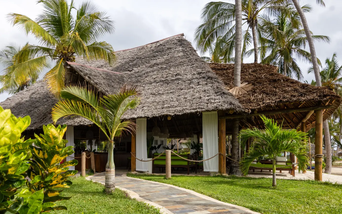 Thatched-roof lodge with palm trees and manicured lawns, Breezes Beach Club & Spa, Zanzibar & Pemba, Tanzania