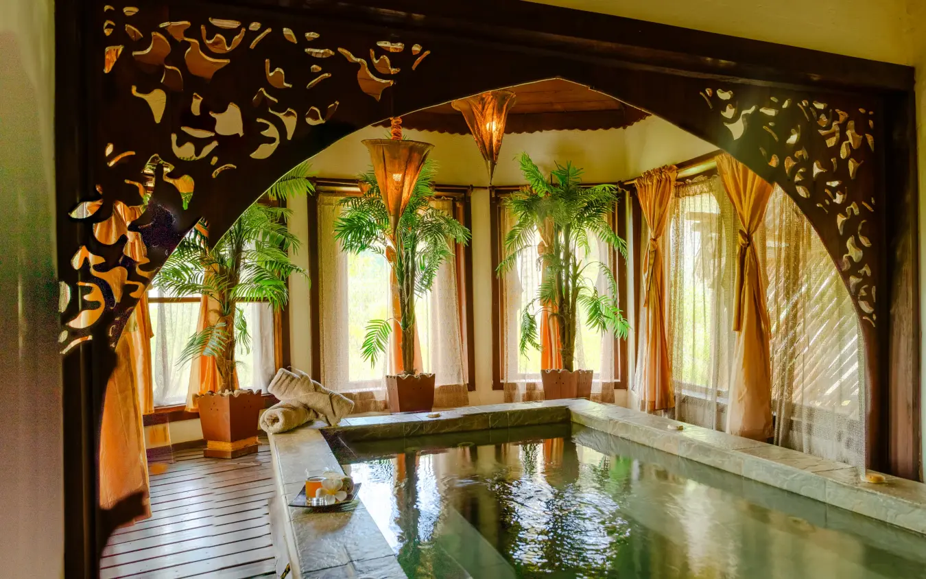 Indoor spa pool with decorative wooden screens and tropical plants by windows, Breezes Beach Club & Spa, Zanzibar & Pemba, Tanzania