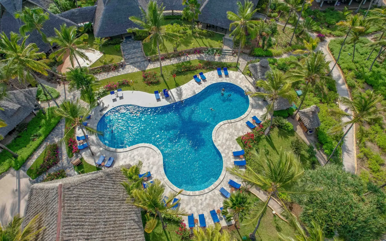 Aerial view of curved swimming pool surrounded by thatched bungalows and palm trees, Breezes Beach Club & Spa, Zanzibar & Pemba, Tanzania