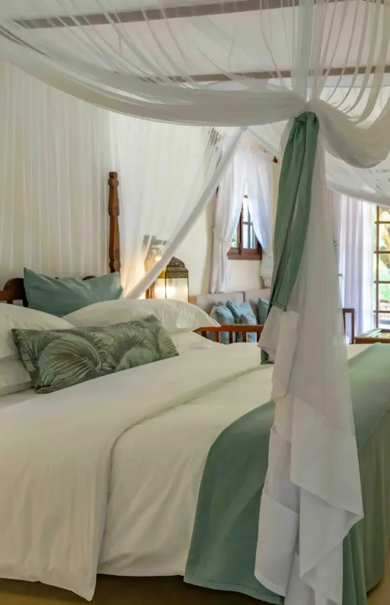 Canopy bed with sheer curtains and green accents in luxury bedroom, Breezes Beach Club & Spa, Zanzibar & Pemba, Tanzania