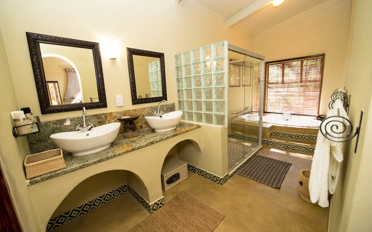 Luxurious bathroom with dual vessel sinks and glass-enclosed shower, Camelthorn Lodge, Hwange National Park, Zimbabwe