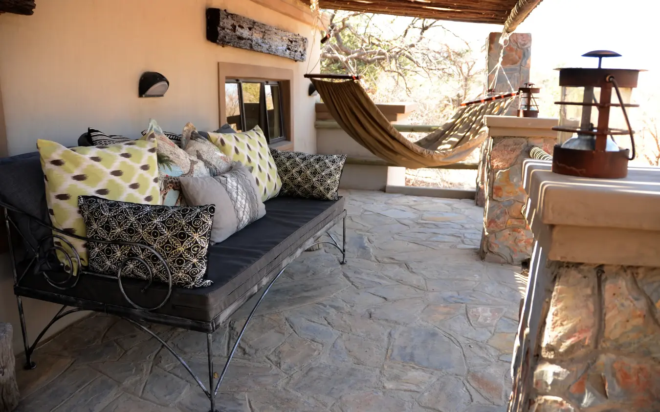 Covered patio with lounge seating and hammock overlooking landscape, Camelthorn Lodge, Hwange National Park, Zimbabwe