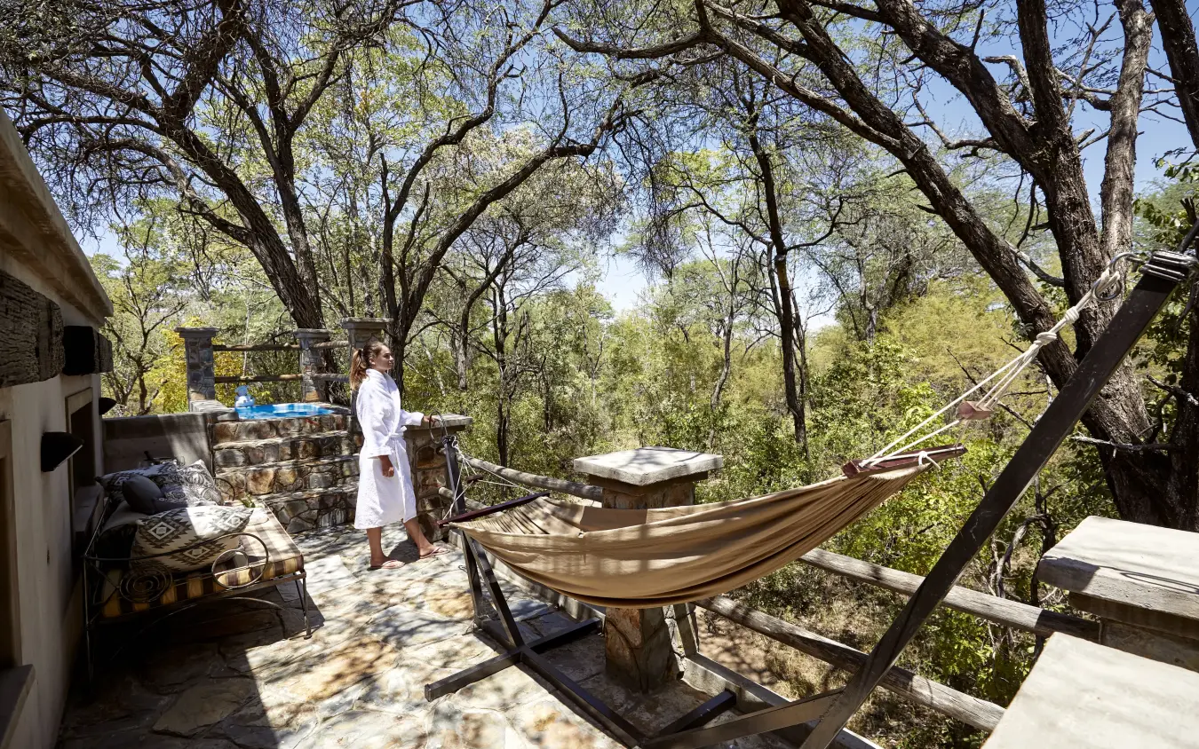 Hammocks on wooden deck beneath sprawling acacia trees with savanna views, Camelthorn Lodge, Hwange National Park, Zimbabwe