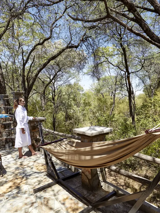 Hammocks on wooden deck beneath sprawling acacia trees with savanna views, Camelthorn Lodge, Hwange National Park, Zimbabwe