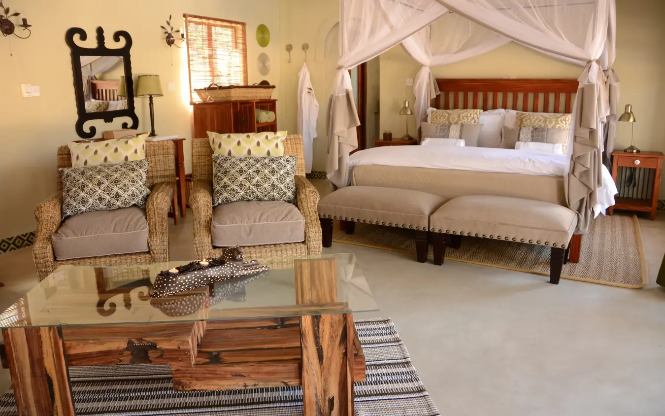 Luxury bedroom suite with canopy bed and sitting area in safari lodge, Camelthorn Lodge, Hwange National Park, Zimbabwe
