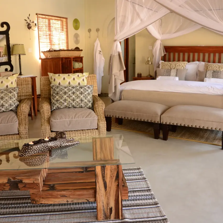 Luxury bedroom suite with canopy bed and sitting area in safari lodge, Camelthorn Lodge, Hwange National Park, Zimbabwe