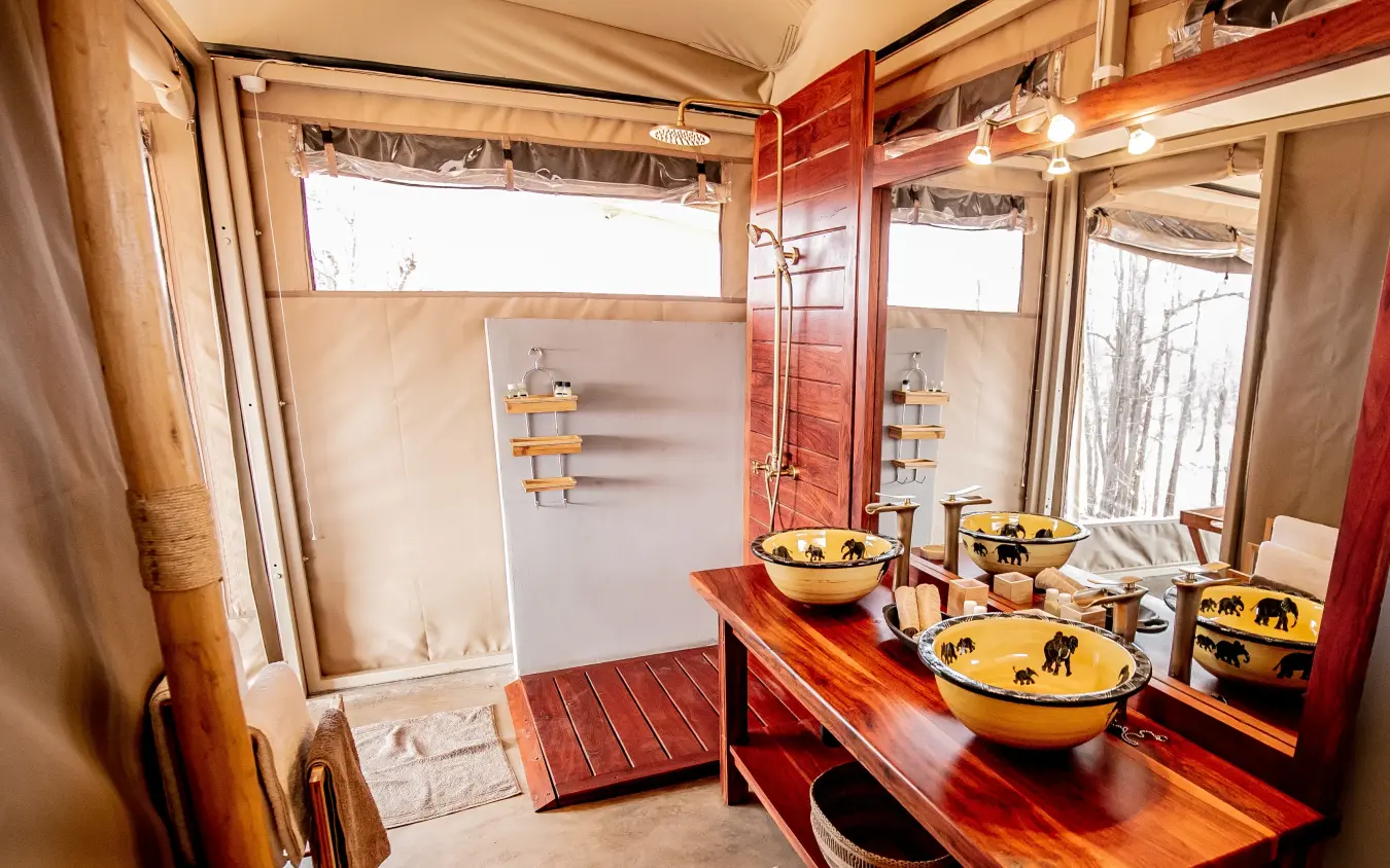 Luxury safari tent bathroom with wooden vanity and decorative bowls, Camp Chitubu, Hwange National Park, Zimbabwe