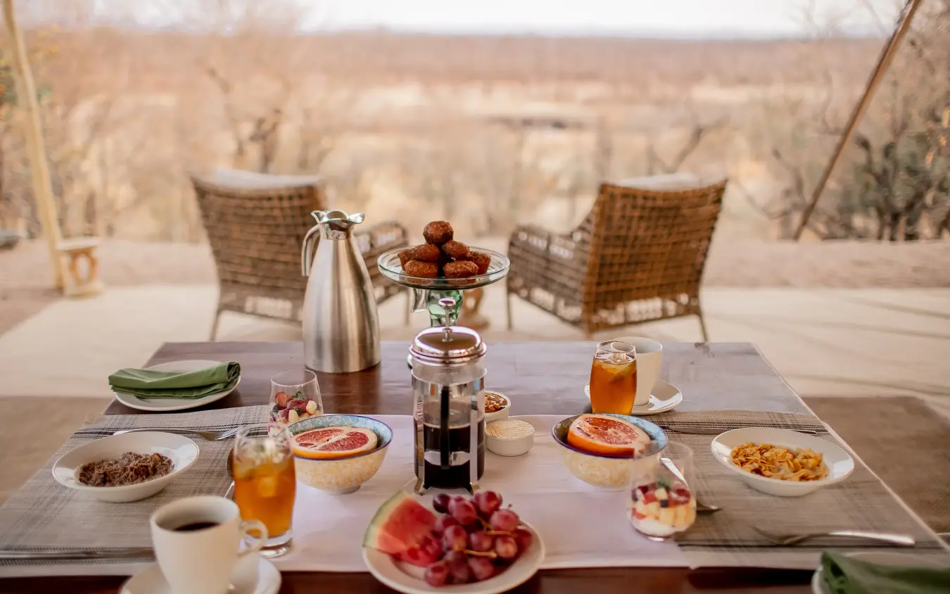 Outdoor breakfast table with savanna landscape view from lodge terrace, Camp Chitubu, Hwange National Park, Zimbabwe
