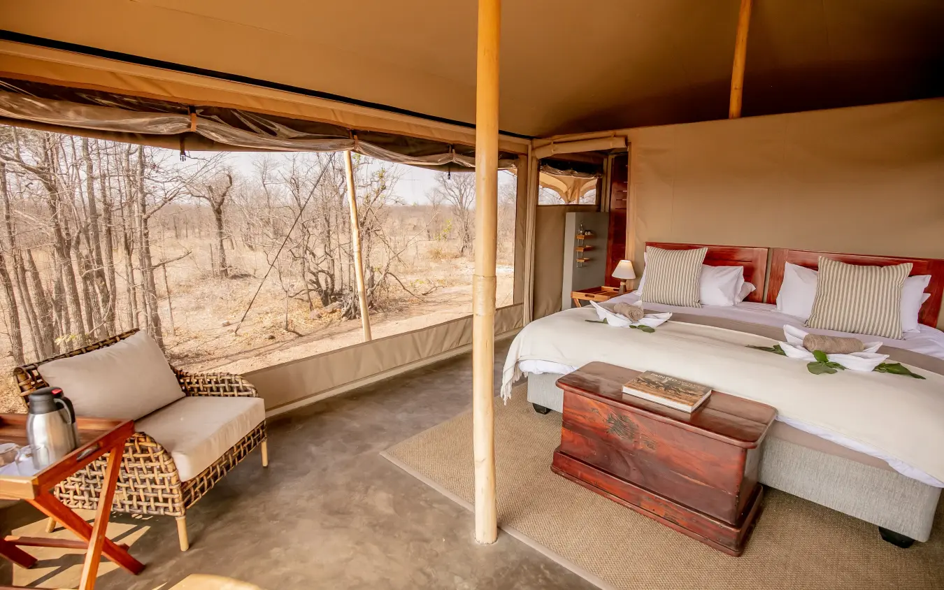 Luxury tent bedroom with viewing deck overlooking bare woodland landscape, Camp Chitubu, Hwange National Park, Zimbabwe