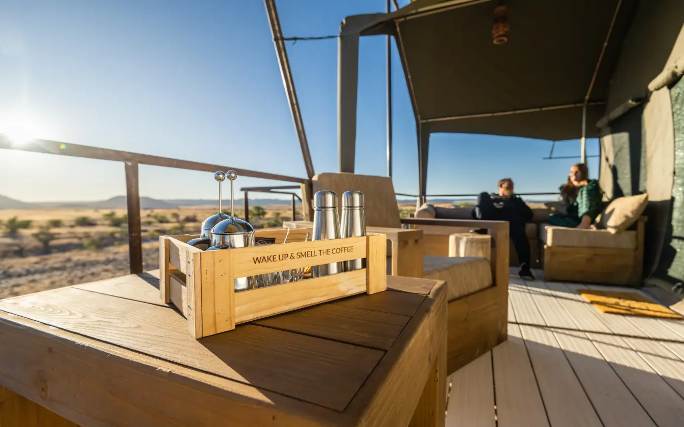 Outdoor deck with coffee service overlooking vast savanna landscape at sunrise, Camp Doros, Damaraland, Namibia