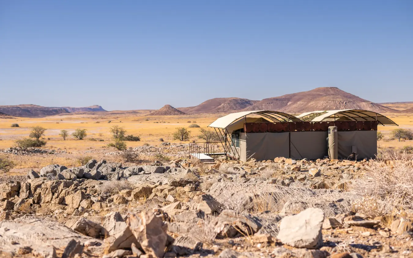 Remote desert camp with canvas structures and rocky terrain, Camp Doros, Damaraland, Namibia