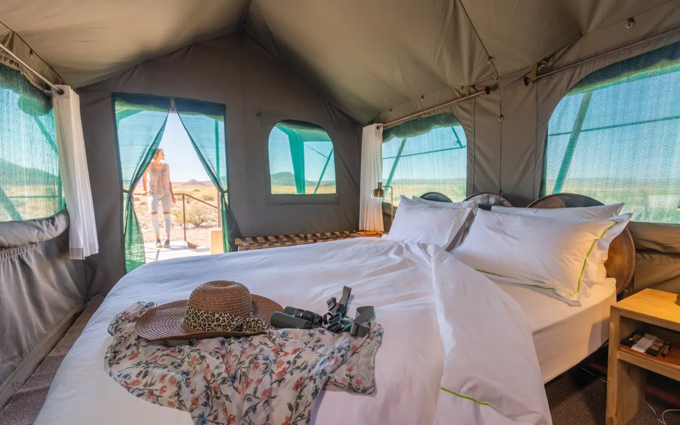 Luxury safari tent interior with beds overlooking arid landscape at sunset, Camp Doros, Damaraland, Namibia