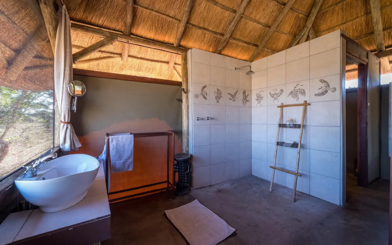 Open-air bathroom with soaking tub and shower area, Camp Hwange, Hwange National Park, Zimbabwe