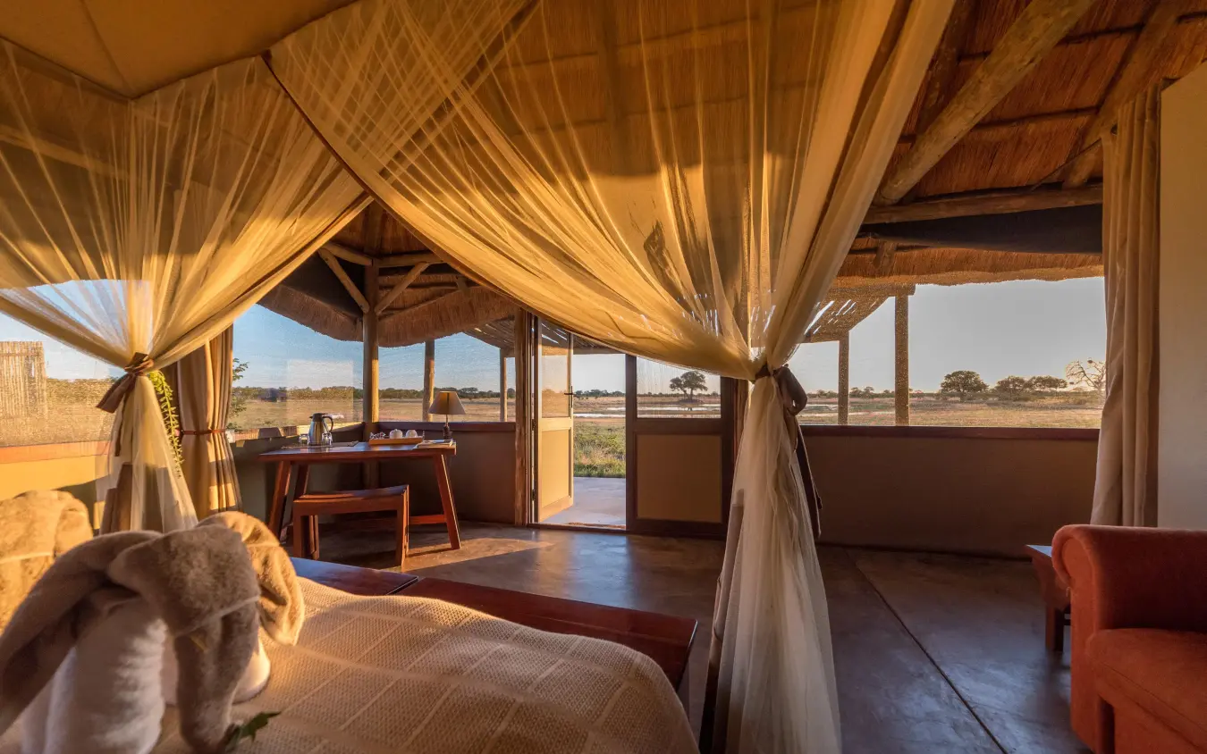 Luxury safari bedroom with four-poster bed and savanna views, Camp Hwange, Hwange National Park, Zimbabwe