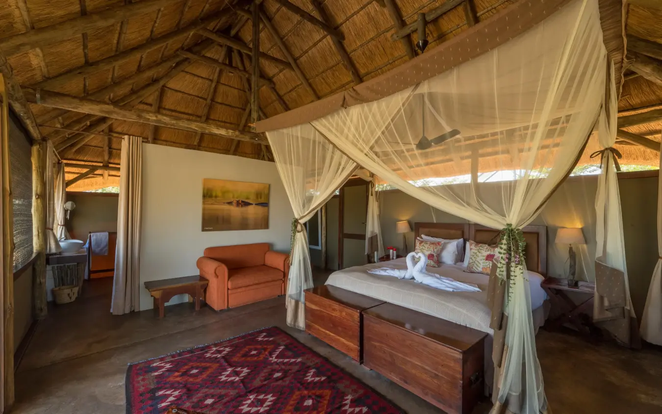 Spacious bedroom with four-poster bed and sheer curtains, Camp Hwange, Hwange National Park, Zimbabwe
