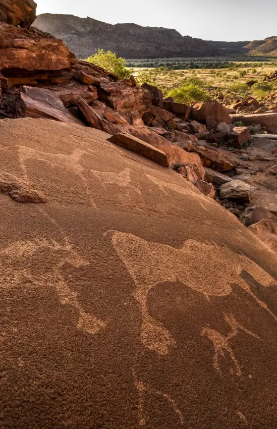 Ancient rock art etched into desert sandstone hillside, Camp Kipwe, Damaraland, Namibia