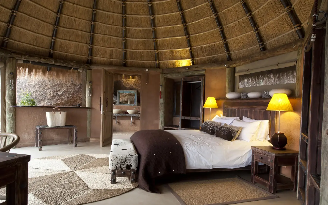Circular thatched-roof bedroom with bed and seating area, Camp Kipwe, Damaraland, Namibia