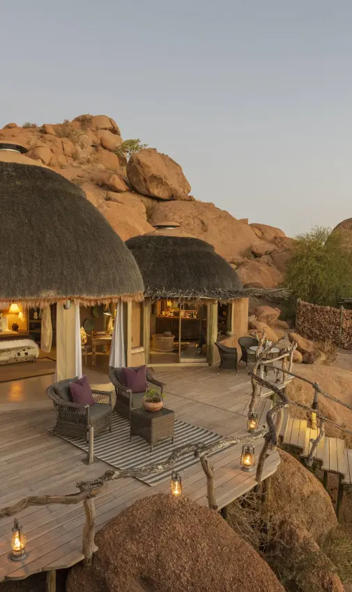 Thatched dome lodge built into rocky granite outcrops at dusk, Camp Kipwe, Damaraland, Namibia