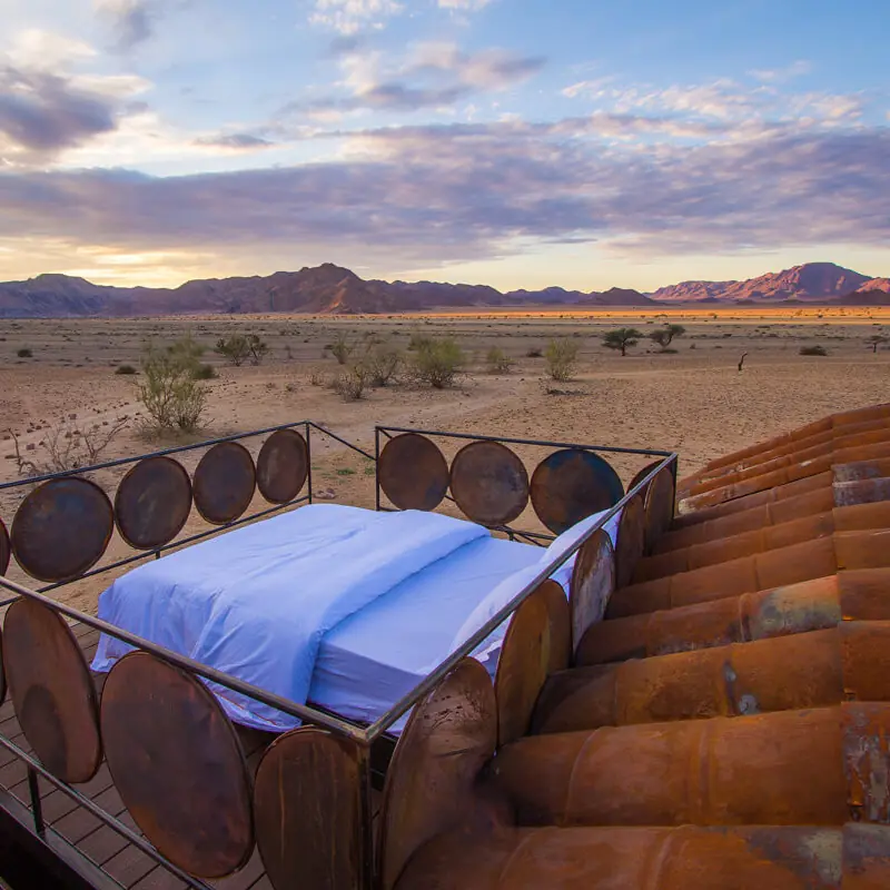 Rustic bed platform overlooking desert landscape at sunset, Camp Sossus, Sossusvlei, Namibia
