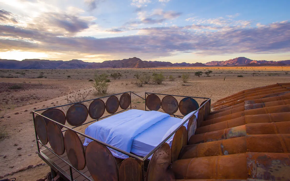 Rustic bed platform overlooking desert landscape at sunset, Camp Sossus, Sossusvlei, Namibia