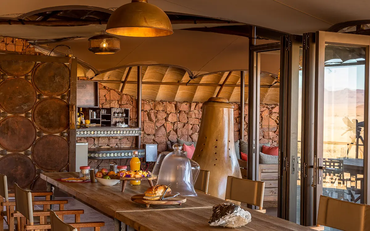 Modern dining area with stone walls and desert views, Camp Sossus, Sossusvlei, Namibia