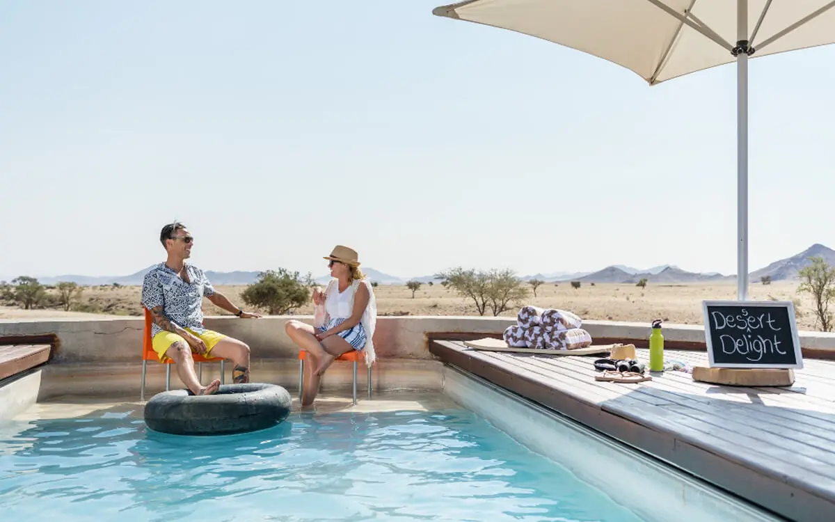 Guests relaxing by pool with desert landscape views, Camp Sossus, Sossusvlei, Namibia