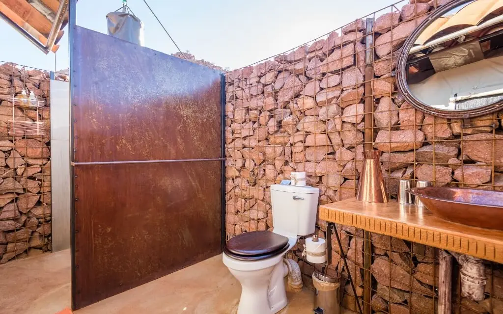 Rustic bathroom with stone walls and copper sink basin, Camp Sossus, Sossusvlei, Namibia