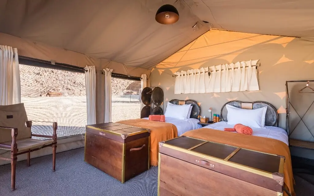 Interior of canvas tent bedroom with two beds, Camp Sossus, Sossusvlei, Namibia