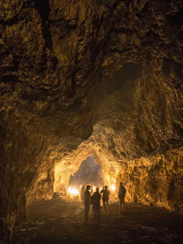 Tourists exploring illuminated cave interior with golden rock formations, Campi ya Kanzi, Amboseli and Chyulu Hills, Kenya