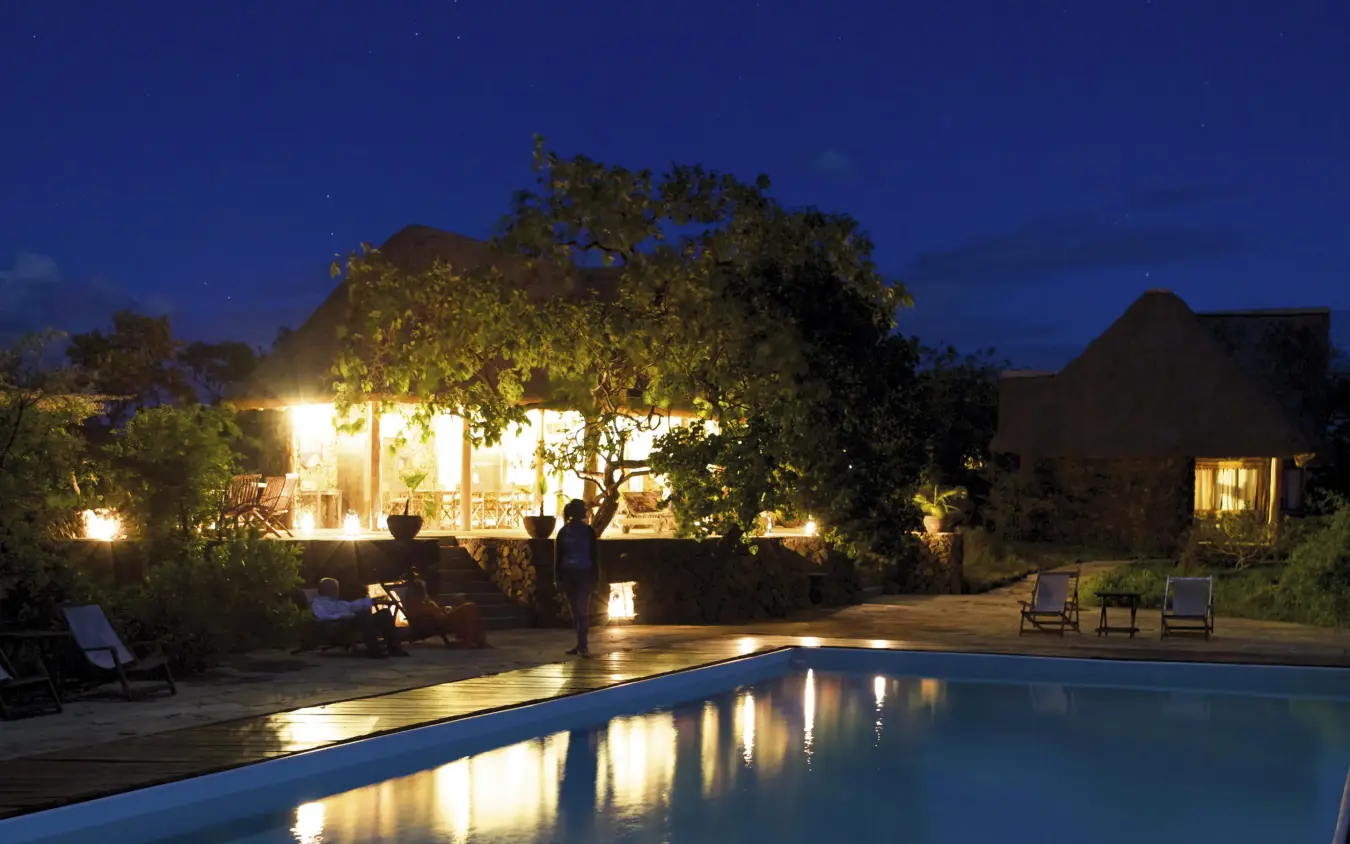 Illuminated swimming pool at night with lodge buildings, Campi ya Kanzi, Amboseli and Chyulu Hills, Kenya