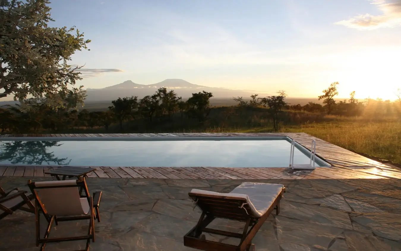 Infinity pool overlooking savanna landscape at sunset, Campi ya Kanzi, Amboseli and Chyulu Hills, Kenya