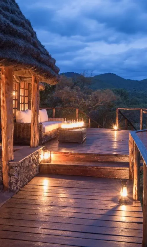 Illuminated wooden deck overlooking forested valley at dusk, Campi ya Kanzi, Amboseli and Chyulu Hills, Kenya