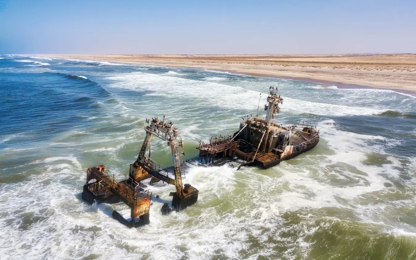 Shipwreck ruins in shallow coastal waters with waves