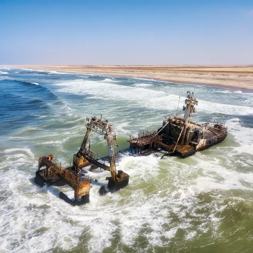 Shipwreck ruins in shallow coastal waters with waves