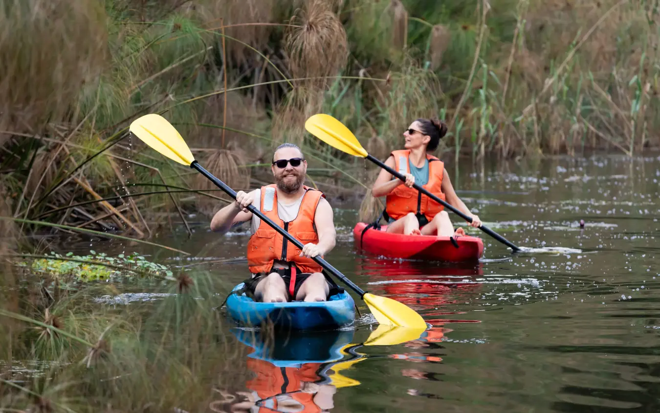 Guests kayaking through reeds on calm water, Chameleon Hill Lodge, Lake Mutanda, Uganda