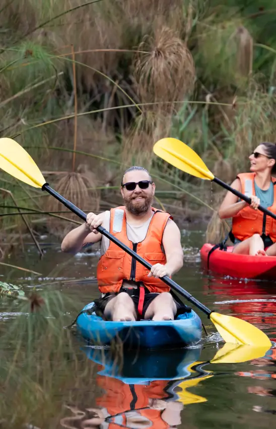 Guests kayaking through reeds on calm water, Chameleon Hill Lodge, Lake Mutanda, Uganda