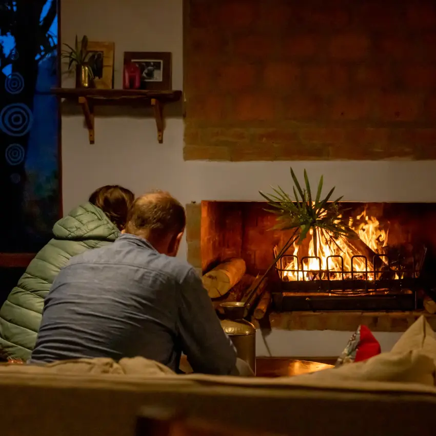 Guests warming by fireplace in evening lounge area, Chameleon Hill Lodge, Lake Mutanda, Uganda