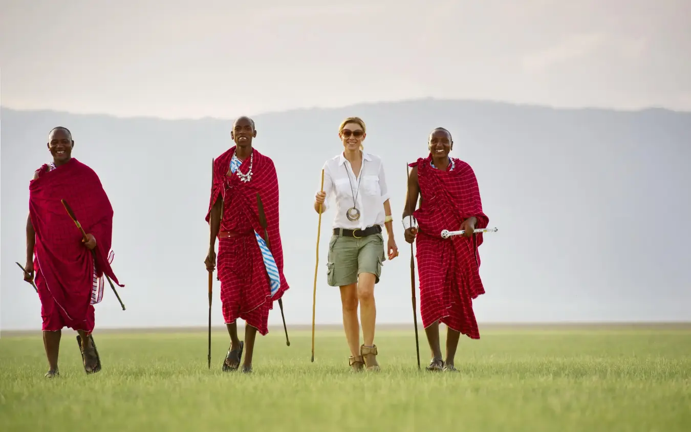 Guides and tourist walking together across open grassland, Chem Chem Lodge, Lake Manyara, Tanzania