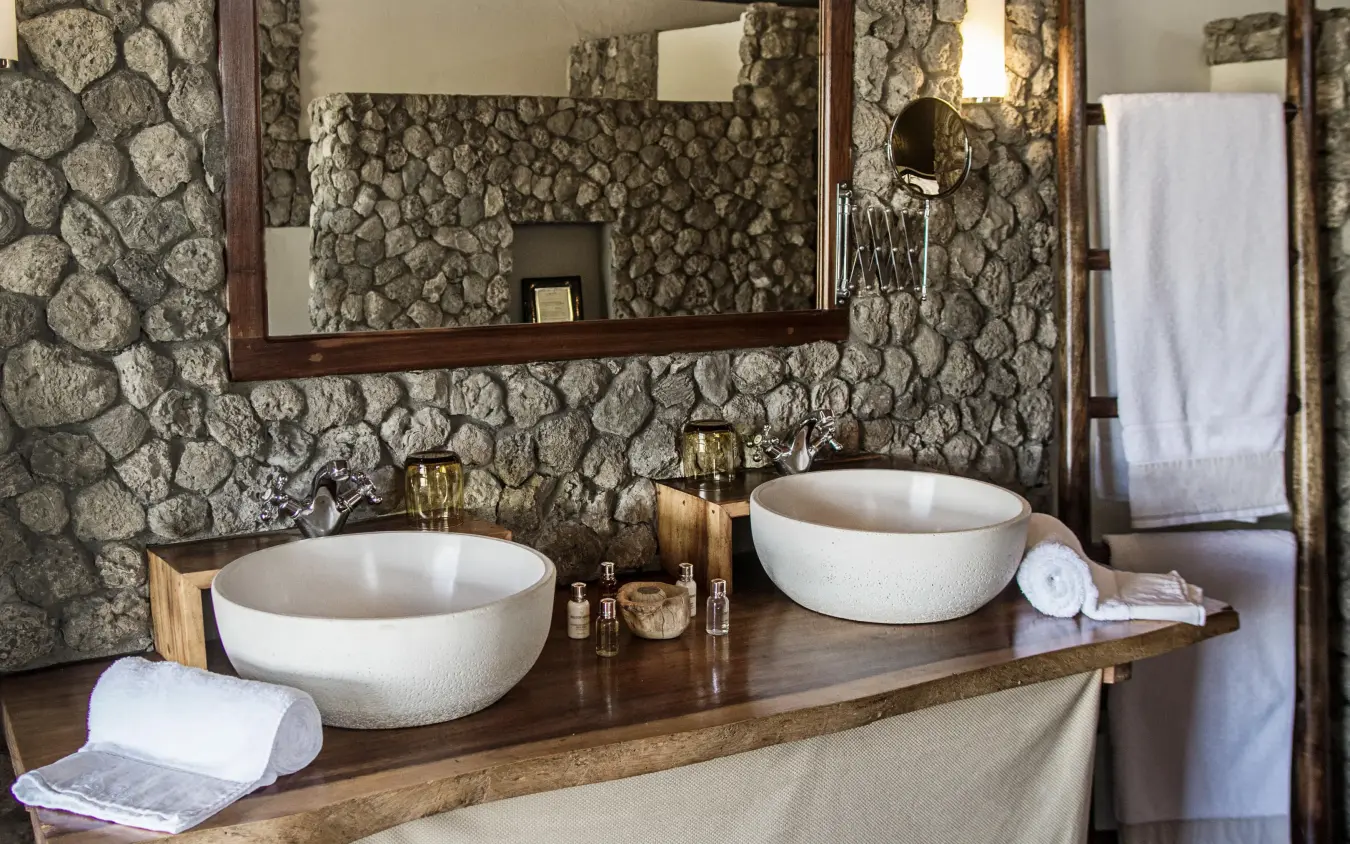 Luxury bathroom with dual vessel sinks and stone walls, Chem Chem Lodge, Lake Manyara, Tanzania