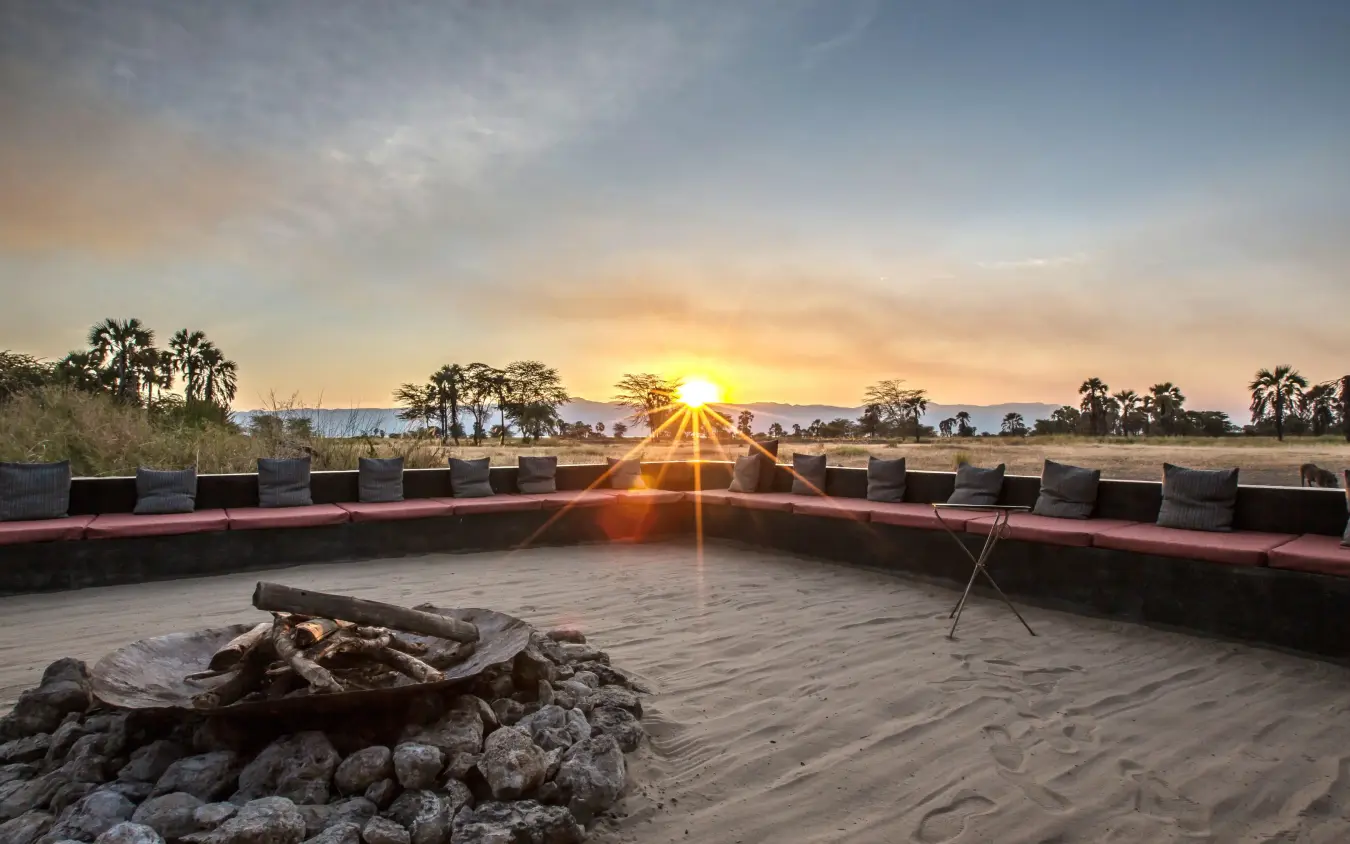 Sunset view from sandy deck with fire pit and seating, Chem Chem Lodge, Lake Manyara, Tanzania